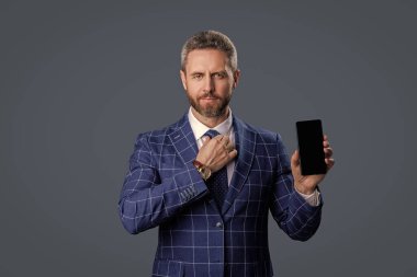 İş adamı takım elbiseli adam telefon ekranında gri ekranda yeni bir uygulama gösteriyor..