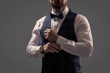 Papyonlu adam gride izole edilmiş. Zarif siyah takım elbiseli şık bir adam. Smokinli bir beyefendi. Resmi etkinlikteki iş adamı. Damadın smokin tarzı var. Centilmen smokini. Smokin, kırpık manzara..