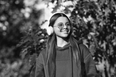 Sonbahar renkleri. Ergenlik konsepti. Sonbahar yürüyüşünde müzik dinleyen mutlu ergen kız. Sonbahar tarzında ergen bir kız. Kulaklıklı kız dışarıda. Merhaba sonbahar.