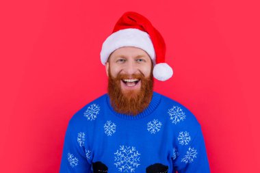 Mutlu Xmas 'lar. Kırmızı arka planda, Noel Baba şapkası ve süveter giyen beyaz bir adam var. Xmas partisindeki adam..