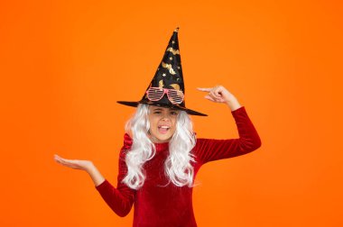 Cadılar Bayramı 'nda cadı şapkası giymiş bir kız. Mutlu Cadılar Bayramı. Cadılar Bayramı kostümlü cadı kız portakalı izole etti. Cadılar Bayramı kostüm partisi kutlaması. Tüm Cadılar Bayramı cadıları. Yarasa şapkası. Reklam..