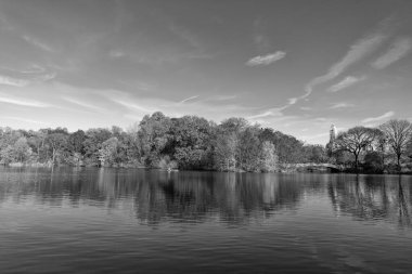 Central Park güneşli sonbahar gününde renk değiştiriyor. Sonbahar manzarası. Sonbahar doğası. Central Park 'ta küçük bir gölde kayık. Sonbaharda Central Park Gölü 'nde insanların kürek çektiği bir yer. Pruva Köprüsü.