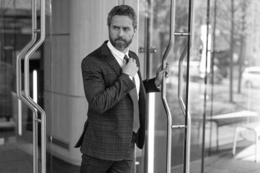 Takım elbiseli İspanyol işadamı ofis binasını terk ediyor. Patron ofisten ayrılıyor. İş adamı. Başarılı bir iş adamı ofise giriyor. Ofis kapısında yetişkin bir girişimci. Deneyimli iş adamı.