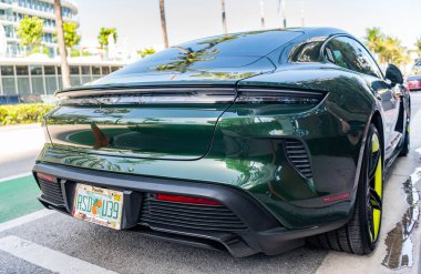 Miami, Florida, ABD - Nisan 06, 2025 Porsche Taycan Turbo S elektrikli spor araba. Elektrikli spor araba Porsche Taycan. Porsche Taycan dışarıda park etmiş. Yeşil elektrikli araba, arka plan..