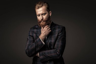 Zarif takım elbiseli hırslı bir adam. Erkekler için resmi moda. Erkek giyim modeli. Takım elbiseli şık bir adam. Sakallı bir iş adamı. Gri yolda yabani sakallı adam. Resmi aksesuarlar.