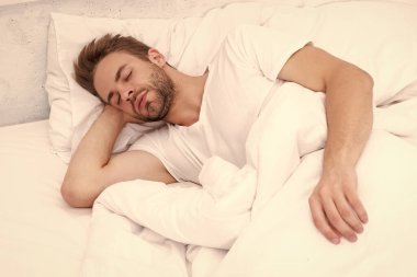 Genç adam uyuyor ya da beyaz yatak odasında evinde uyuyor..