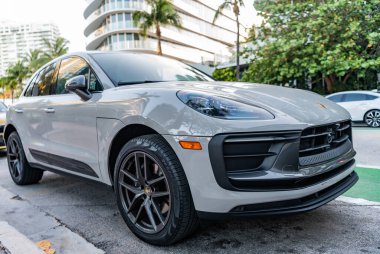Miami, Florida, ABD - 07 Nisan 2025: Porsche Macan açık hava parkı. Beyaz gri araba, köşe manzaralı. 2025 Porsche Macan SUV arabası. Lüks araba Porsche Macan..