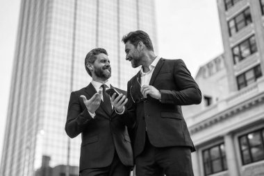 Çalışıyorum. İş adamları iş konuşmalarını kontrol ediyor. İş adamları dışarıda serbest çalışıyor. İnternette iş. Telefonla çalışan adamlar. Çevrimiçi çalışan iş adamları. Takım elbiseli telefonlu iş adamları. İletişim.