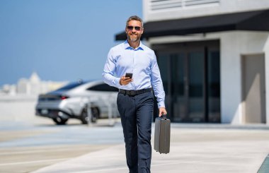 Dışarıdaki telefonda iş adamı sohbeti. İş adamı sokakta telefonda sohbet ediyor. Akıllı telefon kullanan bir iş adamı. Başarılı bir iş adamı internette sohbet ediyor. İş adamı yürüyor. Şirket işi..