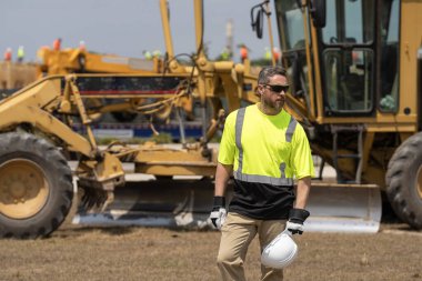 Şantiyedeki adam. İnşaat mühendisliği. İnşaat alanında mühendis var. Denetmen işçi üniforma giyer. İşteki en üst düzey yönetici. İşçi bayramı. Binanın dış tarafında. Güvenliğin sağlanması.