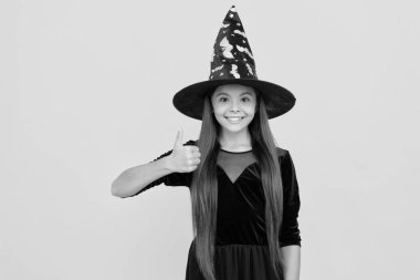 Şeker mi şaka mı? Cadılar Bayramı 'nın tüm bayramlarını kutlayın. Tüm Cadılar Bayramı. 31 Ekim. Cadı kostümlü genç kız. Mutlu Cadılar Bayramı. Cadılar Bayramı kostümlü cadı kız sarıda izole edilmiş. Başparmak yukarı..