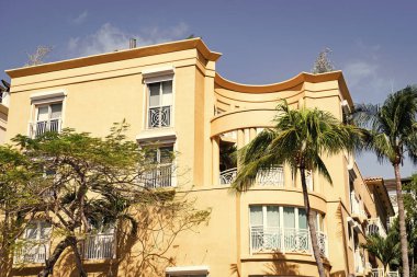 Mimari dış görünüş. Evin dış kısmı parçalanmış. Modern apartman binası. Balkonları ve palmiye ağaçları olan bir apartman. Bina manzarası düşük. Konut mimarisi. Tropikal avuç.