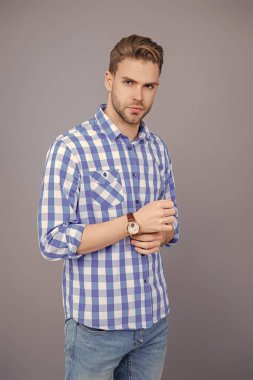 Gri yolda izole edilmiş bir adam. Kareli gömlek giyen milenyum adamı. Milenyum erkeğinin gündelik tarzı. Sıradan tişörtlü bir adamın portresi. Tıraşsız adamın zarif portresi. Günlük kıyafet zorunluluğu.