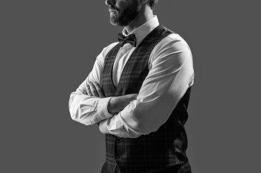 Smokin giymiş şık bir beyefendi. Yeleği ve zarif papyonu var. Gri üzerine izole edilmiş resmi bir etkinlikte..