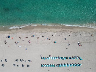 Yaz tatili. Yazın deniz kenarında tatil. Deniz, plaj şemsiyesi altında rahatlar. Denize açılın. Turkuaz suyla kumsalın havadan görünüşü. Lüks tatil köyü. Cennet kumsalı. Sahilde yaşamak.