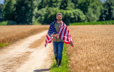 Amerika 'nın Bağımsızlık Günü. 4 Temmuz. Amerikan İşçi Bayramı. Amerikan bayrağı ve çiftçi adam. ABD bayrağı. Bağımsızlık Günü. Sahadaki adam. Ekin tarlasında Amerikan bayrağı taşıyan adam. Bağımsızlık bayrağı.