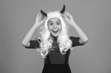 Cadılar Bayramı eğlencesi. Dişi şeytanın Cadılar Bayramı partisinde aksesuarı var. Mutlu Cadılar Bayramı. Cadılar Bayramı partisi için turuncu giysili dişi şeytan hazır. Şeker mi şaka mı? Tüm Cadılar Bayramı parti kutlaması. Kırmızı şeytan boynuzları.