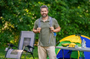 Yaz kampı. Kamp macerası. Yürüyüş yaşam tarzı. Kamp alanındaki adam. Piknik zamanı. Ormanda çadırlı piknik yapan bir adam. Yaz günü yürüyüş yapan bir adam. Yaz kampı aktivitesi. Yürüyüş gezisi.