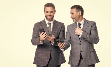 Telefondaki mesajları okuyan iş adamları beyazdan izole edilmiş. İş mesajlaşması. İnternet üzerinden iş mesajlaşması. Takım elbiseli iş adamları telefon kullanır. Mesajlaşan iki işadamı e-postaları kontrol ediyor. Boşluğu kopyala.