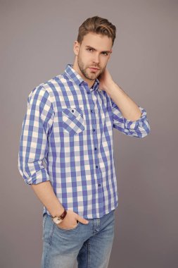 Kareli gömlek giyen milenyum adamı. Milenyum erkeğinin gündelik tarzı. Sıradan tişörtlü bir adamın portresi. Tıraşsız adamın zarif portresi. Gri yolda izole edilmiş bir adam. Günlük düğmeli gömlek..