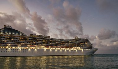 Gece limanında gemi. Lüks deniz tatili. Gemi seyahati. Yaz tatilinde Majestic yolcu gemisi. Gemi seyahati ve deniz seyahati. Aydınlatılmış lüks yolcu gemisi manzarası. Kocaman bir yolcu gemisi..