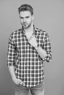 Tıraşsız yüzlü, kendine güvenen genç bir adam ve gri üzerinde izole bir saç stili..