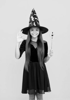 Şeker mi şaka mı? Cadılar Bayramı partisi. Tüm Cadılar Bayramı cadıları. 31 Ekim. Cadı kostümlü genç kız sihirli değneği tutuyor. Mutlu Cadılar Bayramı. Cadılar Bayramı kostümlü cadı kız sarıda izole edilmiş. Tamam..