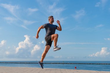 Sağlıklı yaşam tarzı ve günlük koşular. Koşan koşucu. Spor ve spor. Kumsalda koşan adam. Spor yaşam tarzı. Yazın koşan sporcu. Spor koşuculuğu eğitimi. Sabah rutini.