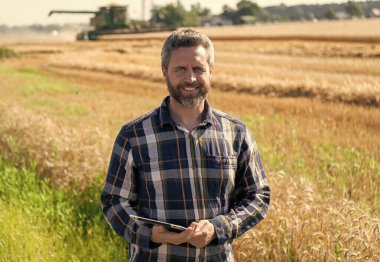 Tarlada tableti olan çiftçi tarımcı adam. Modern tarımın teknolojisi. Tarlada tabletle çalışan çiftçi. Tablet çekli İspanyol çiftçi. Ekin hasadı.