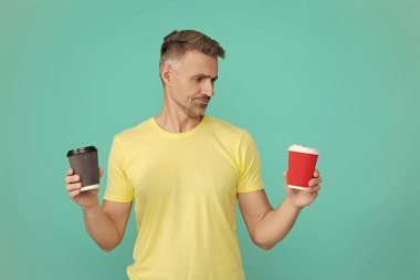 Çay içen adam. Sıcak bir sabah, rahatla. Kahveci adamla kahve molası. Olgun bir adam mavi üzerine kafeinsiz kahve fincanı seçer. Sabah kahvesi vakti. Yaşam tarzı konsepti. Kafeinsiz içiyorum. Paket kâğıt bardak..