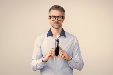 Olgun adam elektrikli jilet sunar. Saç bakım ve tıraş. Kişisel bakım ve günlük rutin işler. Berber dükkanı. Erkek için saç makası. Saç kesme makinesi olan adam. Elinde elektrikli tıraş makinesi olan bir adam. Erkeklerin güzelliği.