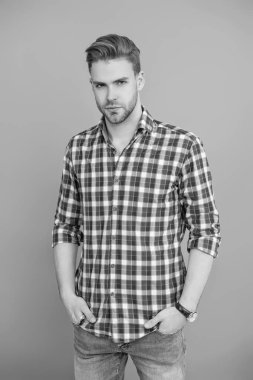 Tıraşsız yüzlü, kendine güvenen genç bir adam ve gri üzerinde izole bir saç stili..