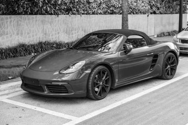 Miami Beach, Florida USA - 9 Haziran 2024: 2018 Porsche 718 Boxter 's orange color at Miami Beach. Ocean 'daki lüks araba porshche' si Miami plajına gidiyor. ön görünüm