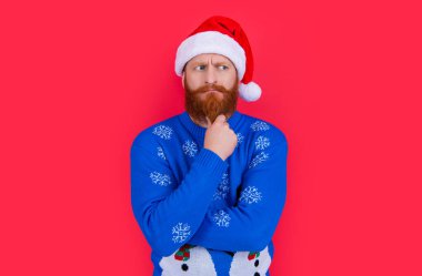 Yeni yıl süveteri ve kırmızı arka planda izole edilmiş Noel Baba şapkası giyen beyaz bir adam. Yılbaşı partisindeki adam. Mutlu yıllar..