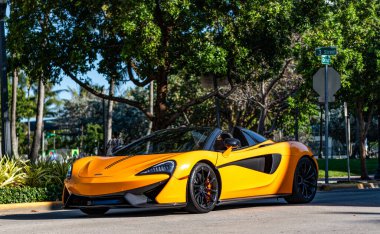 Miami, Florida, ABD - 07 Nisan 2025: lüks turuncu spor araba McLaren GT. McLaren GT 'nin arabası dışarı park edilmiş, yan manzaralı. 2016 McLaren 570 üstü açık spor araba.