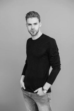 Tıraşsız yüzlü, kendine güvenen genç bir adam ve gri üzerinde izole bir saç stili..