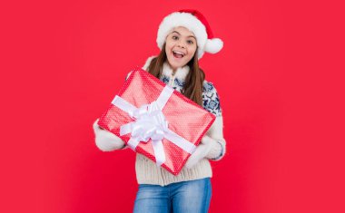 Noel tatili. Stüdyoda noel hediyesi olan genç kız şaşırdı. Genç kız Noel Baba 'yı kırmızı arka planda izole bir şekilde bekletiyor..