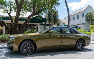 Miami, Florida, ABD - 18 Nisan 2025: Araç 2024 Rolls Royce Ghost açık havada park etti. Altın araba, yan görüş. 2024 Rolls Royce Hayalet sedan arabası. Lüks sedan araba Rolls Royce Hayalet.