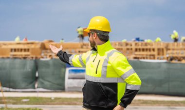 Denetmen işçi üniforma giyer. İşteki en üst düzey yönetici. İşçi bayramı. Binanın dış tarafında. Şantiyedeki adam. İnşaat mühendisliği. İnşaat alanında mühendis var. Proje sunuluyor.