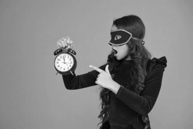 Parti geri sayımı. Parti maskeli, saati olan genç bir kız. Parti sonrası eve geç gelen bir kız. Tatil eğlencesi bitti. Geri sayım. Geç kalan kız turuncudan izole edilmiş. Geç saatte. İşaret parmağı.