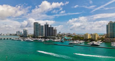 Miami marinasındaki lüks yatların hava manzarası. Miami marinasındaki tekne ve gökdelenlerin manzarası. Miami kıyı şeridi boyunca yelken açan yat.