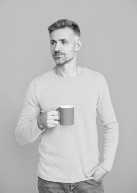 Yaşam tarzı konsepti. Espresso içiyorum. Çay içen adam. Sıcak bir sabah. Evde kahve molası. Maviye izole edilmiş kahve fincanı olan olgun bir adam. Sabah kahvesi vakti. İyi titreşimler..