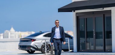 Takım elbiseli İspanyol iş adamı. İş başarısı. Başarılı bir iş adamı yürüyor. Başarılı bir iş adamı park yerinde evrak çantasıyla yürüyor. İş adamı evrak çantasını tutar. Liderlik başarısı.