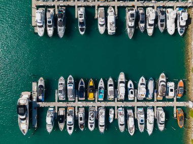 Marinaya yanaşmış lüks yatların havadan görüntüsü. Yatların yukarıdan aşağıya insansız hava aracı görüntüsü. Tekneler ve yelkenliler Manzaralı deniz kıyısında