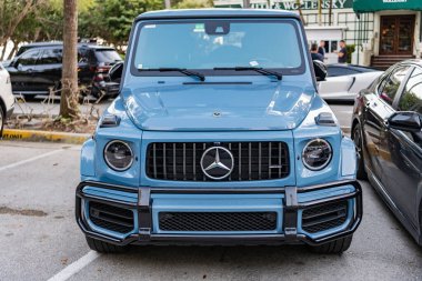 Miami, Florida, ABD - 16 Şubat 2025: Lüks elektrikli ve motorlu Mercedes Benz G sınıfı. Mercedes Mercedes Benz hibrit araba dışarıda park halinde. Mavi araba, ön manzara. 2024 Mercedes Benz G sınıfı hibrit araba.