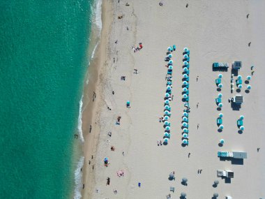 Lüks tatil köyü. Cennet kumsalı. Yaz tatili. Yazın deniz kenarında tatil. Deniz, plaj şemsiyesi altında rahatlar. Denize açılın. Turkuaz suyla kumsalın havadan görünüşü. Sakin bir gün..