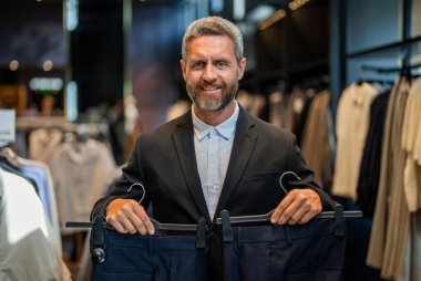 Takım elbiseli manken. Perakende asistanı şık bir adamın pantolon bulmasına yardım ediyor. Pantolonu olan şık bir adam. İş adamı mağazadan şık pantolonlar seçer. İspanyol adam terzi pantolonu seçiyor. Bespoke terzilik.