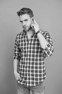 Adam gri renkte izole edilmiş kulaklık kullanıyor. Modern kablosuz kulaklıklar. Elsiz kulaklık. Kulaklık cihazı aksesuarı. Kablosuz kulaklık cihazı. Aletli adam. Kablosuz kulaklıklı bir adam. Kulaklık Kullanımı.