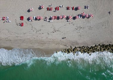 Güneş yatağı ve şemsiyeli kumsal manzarası. Yaz tatili. Yazın deniz kenarında tatil. Deniz, plaj şemsiyesi altında rahatlar. Denize açılın. Lüks tatil köyü. Plaj tatili.