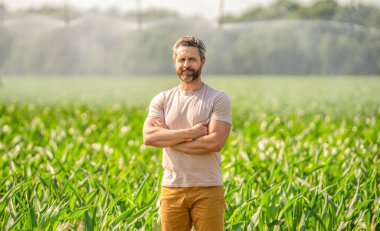 Çiftçi adam. Su fıskiyesi sulama alanı. Damlatma sulama sistemi. Ekin sulama. Tarım ve tarım. Sulama sisteminde tarımı sulayan profesyonel bir adam. Fıskiye sulama.